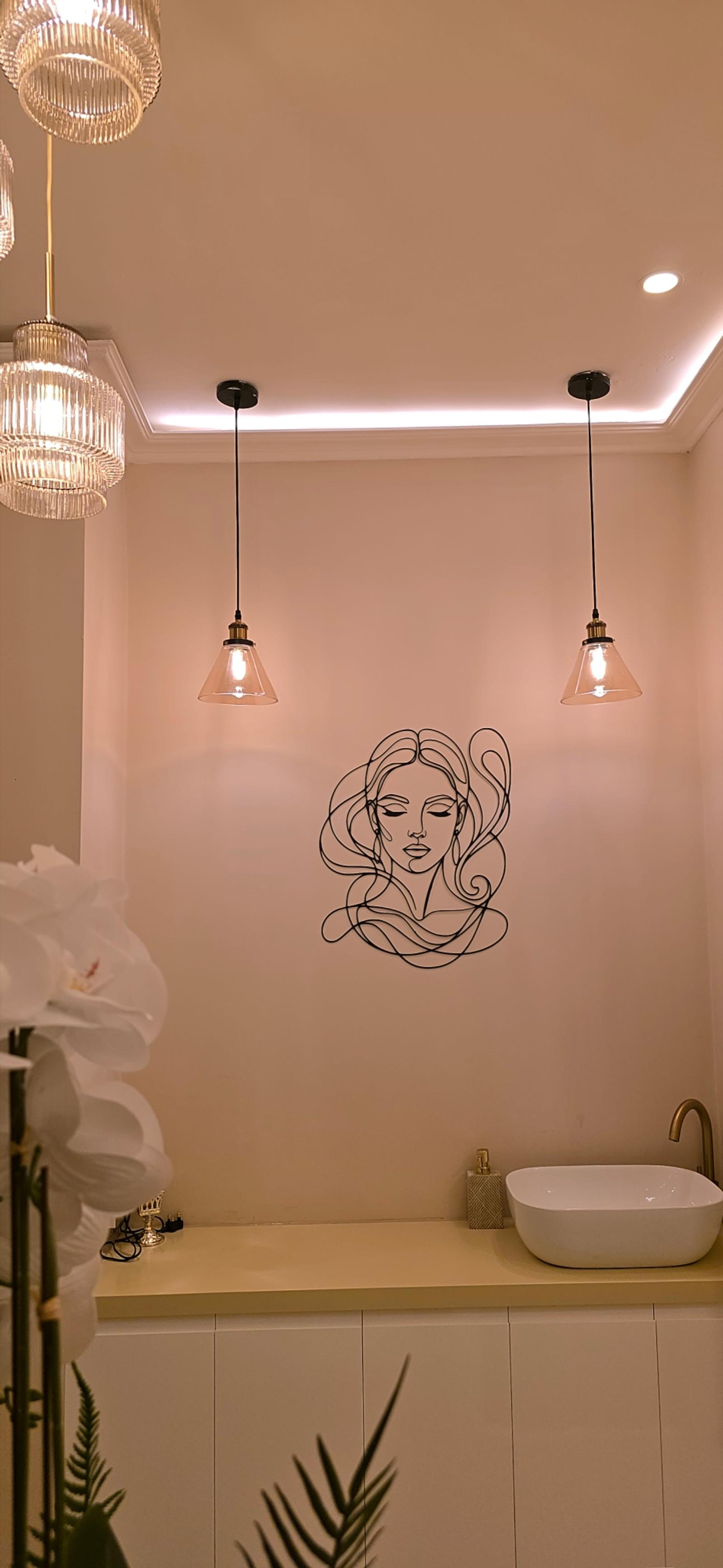 Gazals powder room with ribbed-glass and amber pendant lights, wire portrait art, white orchids and a vessel sink with a brass tap